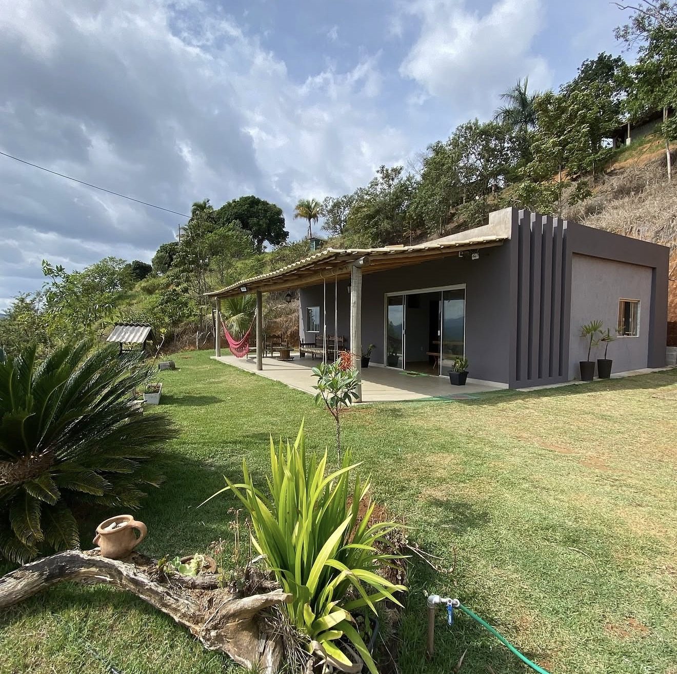 A casa do sítio com a varanda, a rede e o gramado